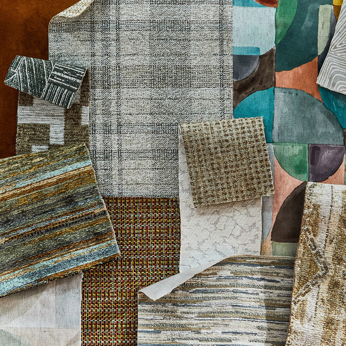 Assorted Revolution Performance Fabric samples in various colors, patterns, and textures, displayed in an overlapping arrangement. The samples include stripes, geometric designs, and textured weaves, showcasing the diversity of upholstery fabric options.